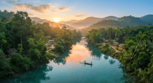 The Gomati River flowing through Tripura with lush green forests, bamboo groves, rural villages, rolling hills, and traditional fishing boats