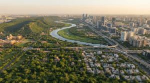 Aerial view of Delhi showing the Yamuna River, Delhi Ridge, green parks, modern skyline, highways, and urban landscape.