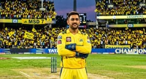 MS Dhoni in yellow Chennai Super Kings jersey with wicketkeeping gloves at Chepauk stadium with yellow-clad fans cheering